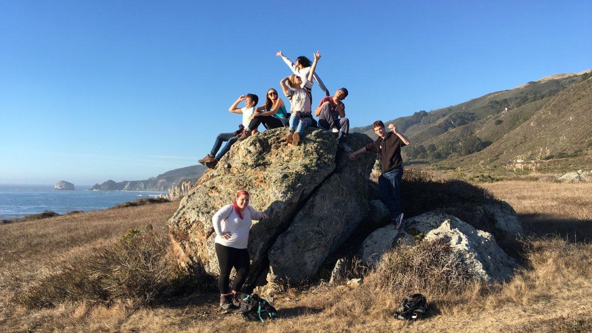 EES students on fieldtrip posing on a coastal rock above the ocean